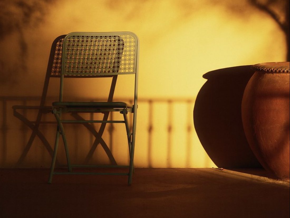 pellicule couleur chaude — une chaise sur une terrasse baignée par la lumière dorée de fin de journée