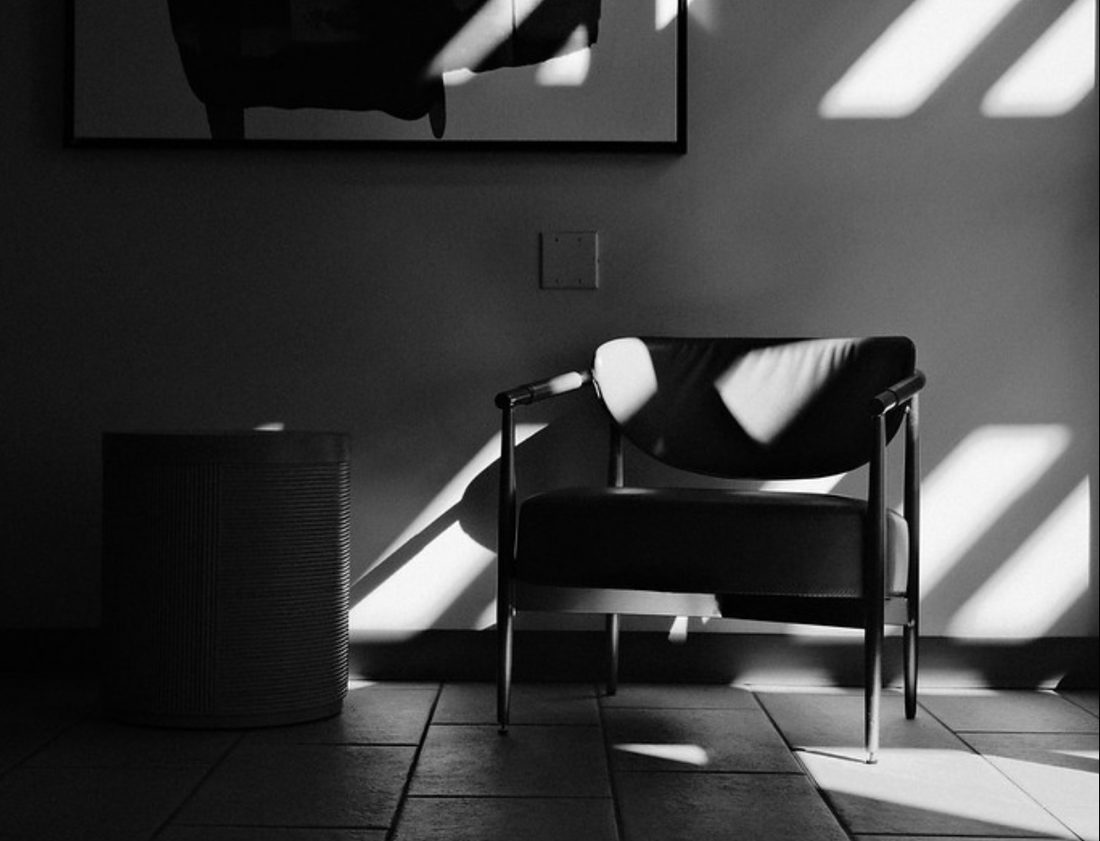 pellicule noir et blanc — un fauteuil et un mur traversés par des ombres découpées
